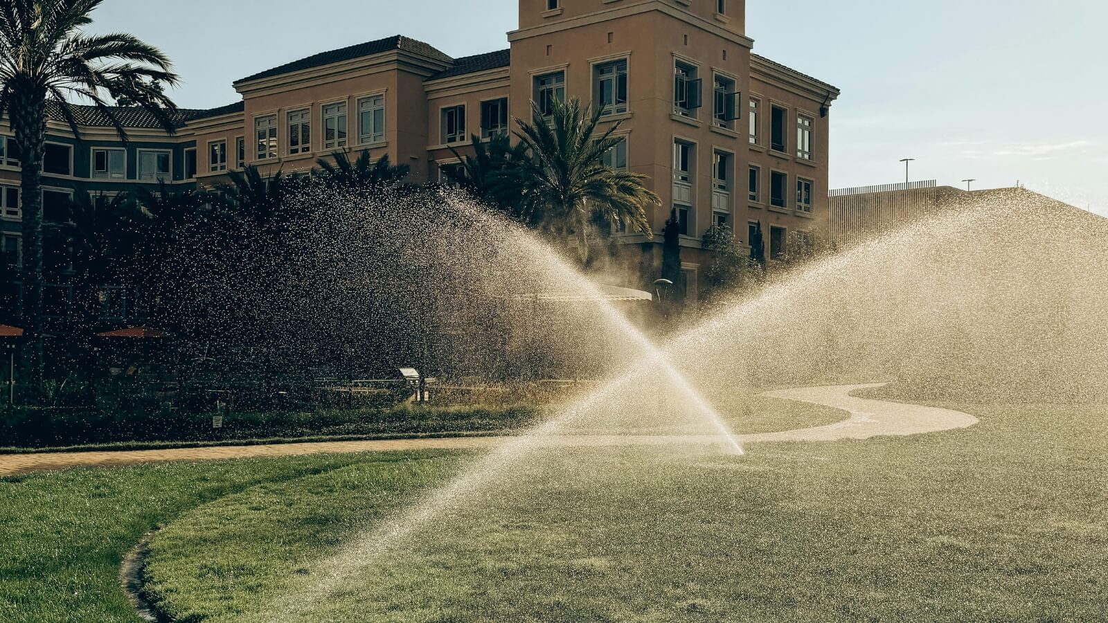 sprinkler is spraying water on the grass in front of a building