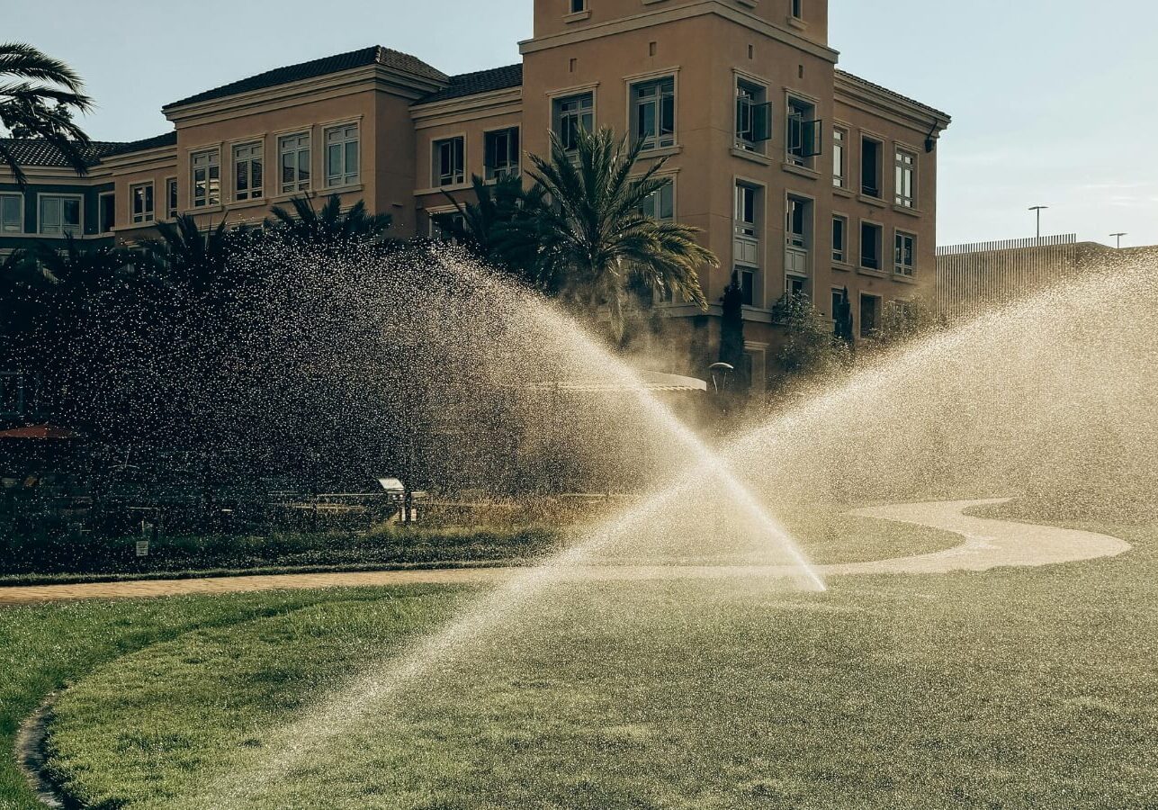 sprinkler-system-commercial-building sprinkler is spraying water on the grass in front of a building